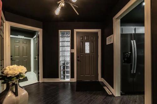 A modern entryway with dark walls, a glass block window, and a sleek refrigerator visible in the background.