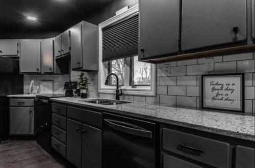 A modern kitchen with dark cabinets, a granite countertop, and a window overlooking a snowy landscape.