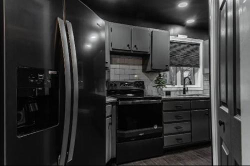 A modern kitchen featuring black appliances, dark cabinets, and a window with blinds, creating a sleek, contemporary look.