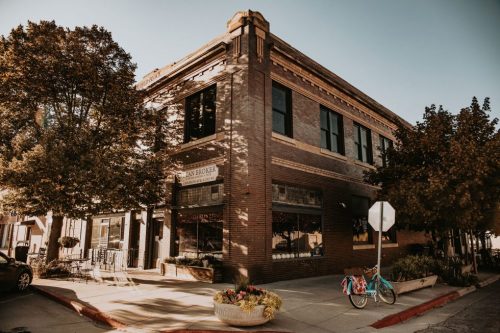 Historic brick building on a sunny day, with trees and a bicycle parked nearby.