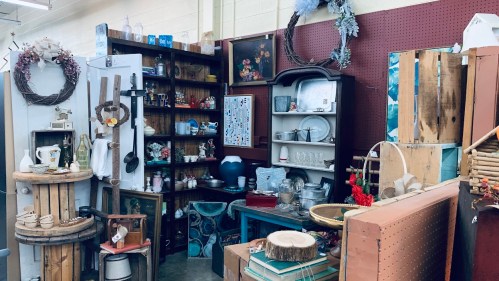 A cozy vintage shop display featuring shelves of decor, furniture, and various collectibles in warm, inviting colors.