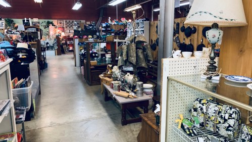 A vintage shop aisle filled with various antiques, hats, and decorative items on display.