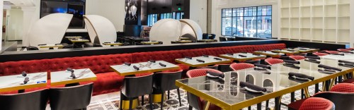 Modern restaurant interior featuring red upholstered seating, elegant tables, and unique dome-shaped booths.