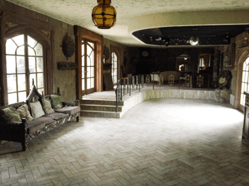 A spacious, elegantly designed room with arched windows, a curved staircase, and decorative furnishings.