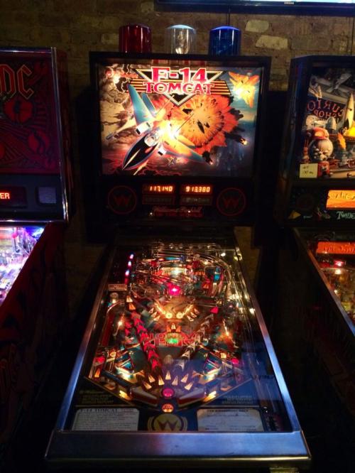 A colorful pinball machine featuring a fighter jet and vibrant artwork, illuminated with lights and buttons.
