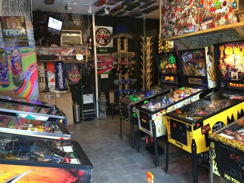 A vibrant arcade filled with colorful pinball machines and retro decor, creating a lively gaming atmosphere.