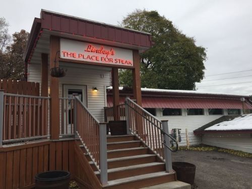 Exterior of Lindy's restaurant, featuring a sign that reads "THE PLACE FOR STEAK" and a welcoming entrance with stairs.