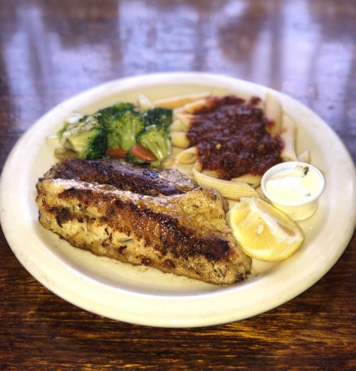 A plate featuring grilled fish, pasta with marinara sauce, steamed broccoli, and a lemon wedge.