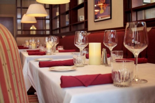 Elegant restaurant setting with white tablecloths, wine glasses, and soft lighting, creating a cozy atmosphere.