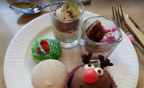 A plate of colorful desserts, including a green cupcake, chocolate mousse, and a reindeer-themed treat.