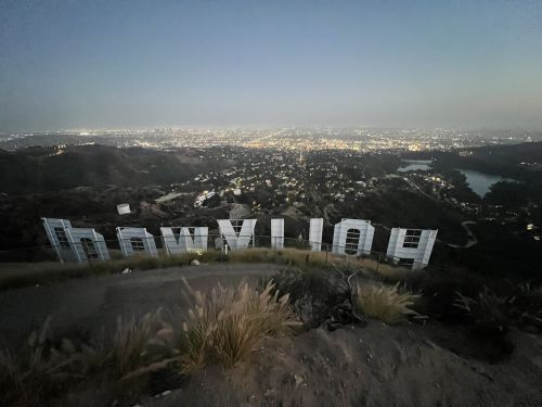View of the Hollywood sign at dusk, overlooking a cityscape filled with lights and hills in the background.