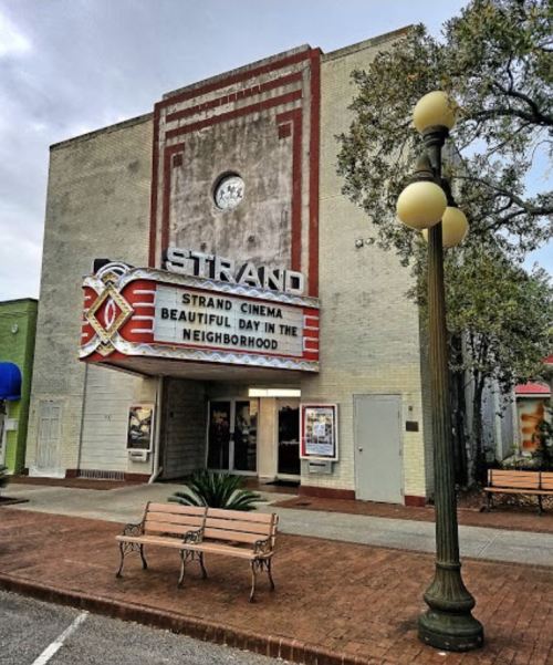 Exterior of the Strand Cinema featuring a marquee for "Beautiful Day in the Neighborhood" and nearby benches.