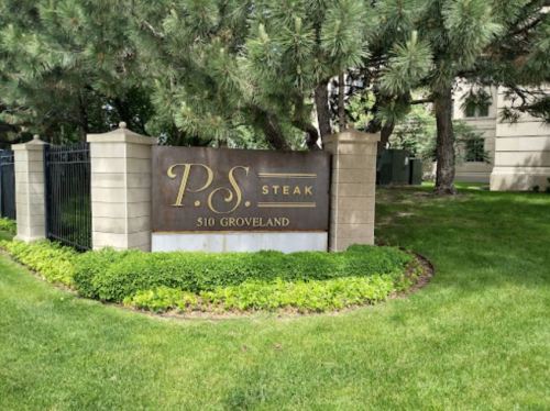 Sign for P.S. Steak located at 510 Groveland, surrounded by greenery and trees.