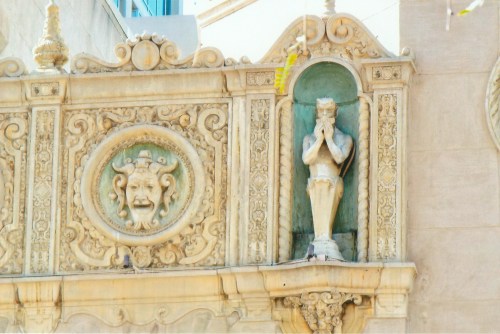 Ornate architectural detail featuring a statue and decorative reliefs on a building facade.