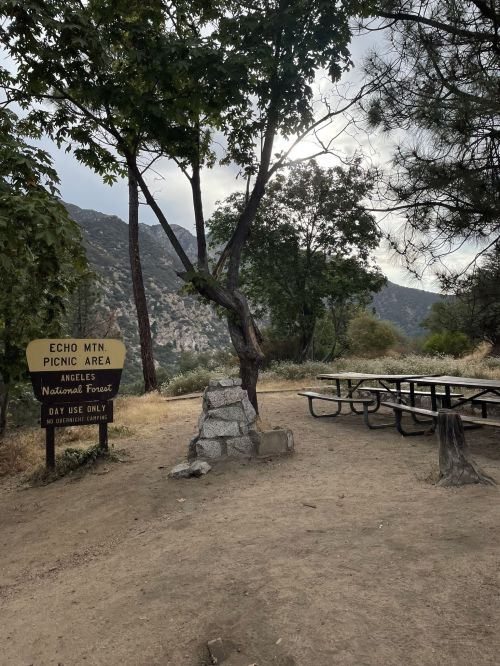 Sign for Echo Mountain Picnic Area in Angeles National Forest, with picnic tables and trees in a natural setting.