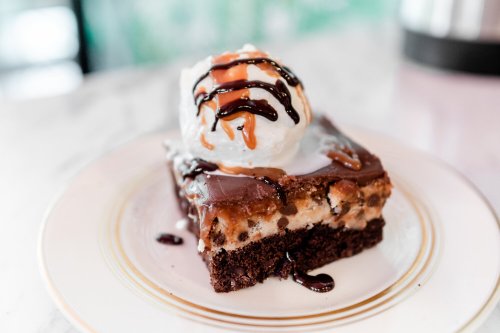 A decadent chocolate dessert topped with vanilla ice cream and drizzled with chocolate and caramel sauces.