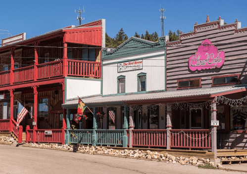 Colorful historic buildings line a street, featuring shops with decorative facades and American flags.