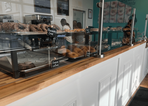 A display case filled with various pastries and donuts in a bright, modern bakery.