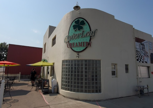 Exterior of Clover Leaf Creamery, featuring a round building with a green sign and colorful umbrellas outside.