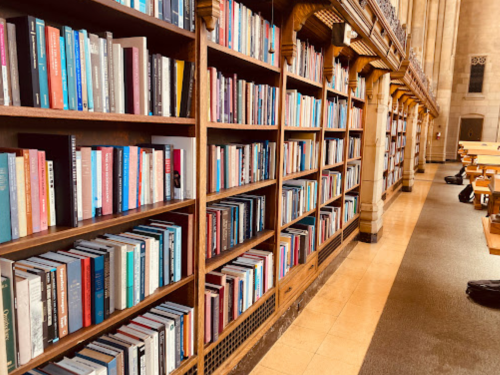 A library interior featuring tall wooden bookshelves filled with various books and a quiet study area.
