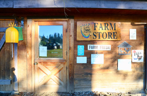 A wooden farm store entrance with a sign reading "Farm Store" and various farm-related posters and information.