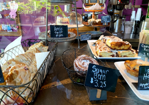 A display of assorted baked goods, including pastries and cinnamon rolls, with price tags on a counter.