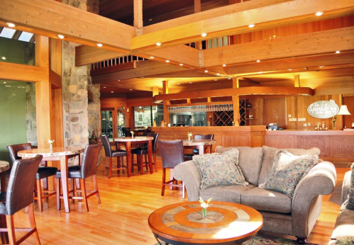 Cozy interior of a rustic lounge with wooden beams, a bar, and comfortable seating. Warm lighting enhances the ambiance.