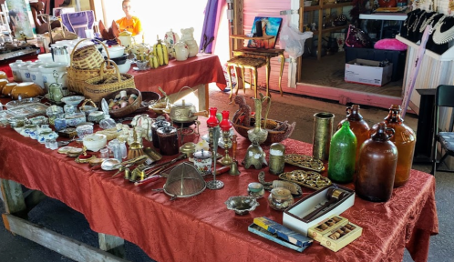 A vibrant market table filled with various antiques and collectibles, including glassware, pottery, and decorative items.