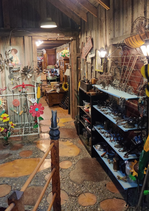 A rustic interior with wooden walls, colorful decorations, and various handcrafted items displayed on shelves.