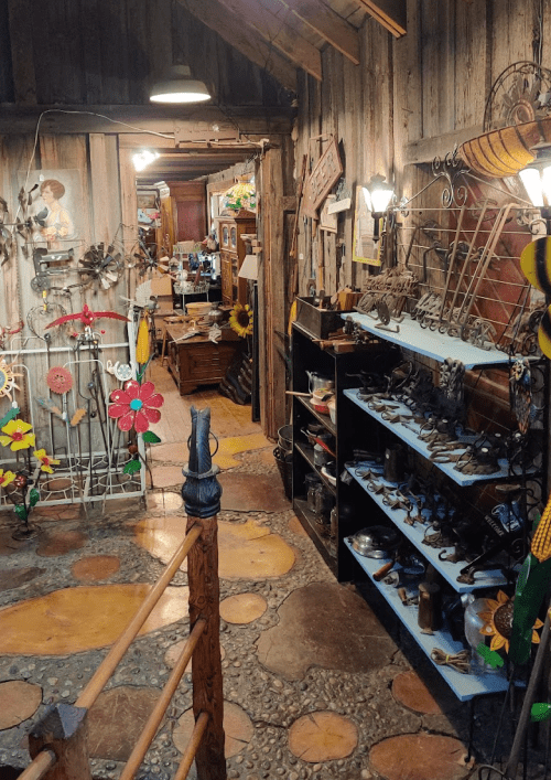 A rustic interior with wooden walls, colorful decorations, and various handcrafted items displayed on shelves.