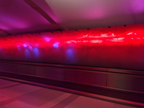 A brightly lit tunnel wall with vibrant red and blue lights creating an abstract, colorful pattern.