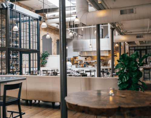 A modern restaurant interior featuring a spacious dining area, open kitchen, and industrial design elements.