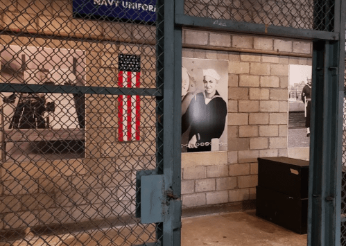 A fenced area with black and white historical photos and a small American flag on the wall.