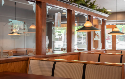 Cozy restaurant interior with wooden booths, glass partitions, and pendant lighting.