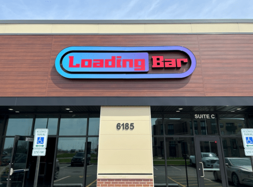 Sign for "Loading Bar" on a building exterior, featuring colorful lettering and a modern design.