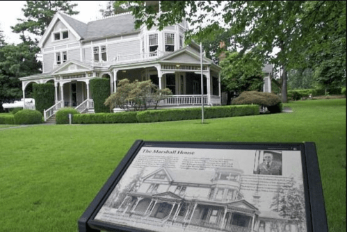 Historic Marshall House with a sign in front, surrounded by lush greenery and a well-maintained lawn.