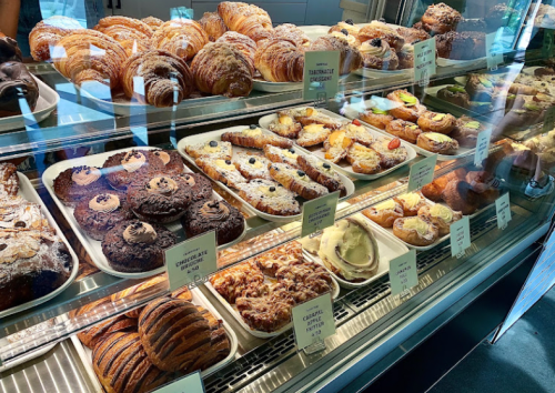 A display case filled with various pastries, including croissants, danishes, and chocolate treats.
