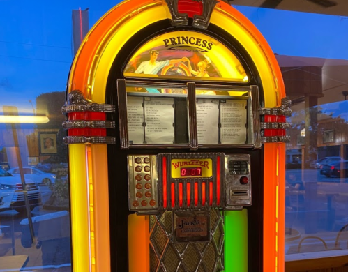A colorful vintage jukebox with bright lights and a classic design, featuring song selections and a glowing display.