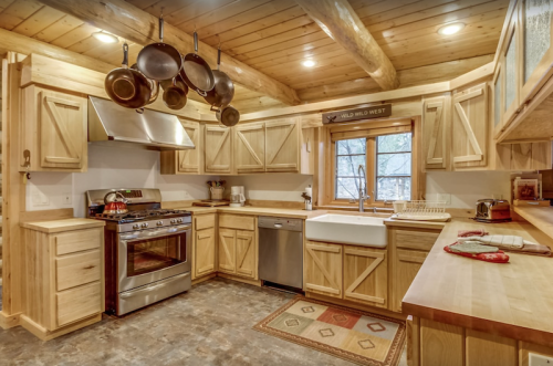 Cozy wooden kitchen with stainless steel appliances, a farmhouse sink, and pots hanging above the counter.