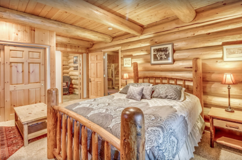 Cozy log cabin bedroom featuring a wooden bed, warm lighting, and rustic decor.