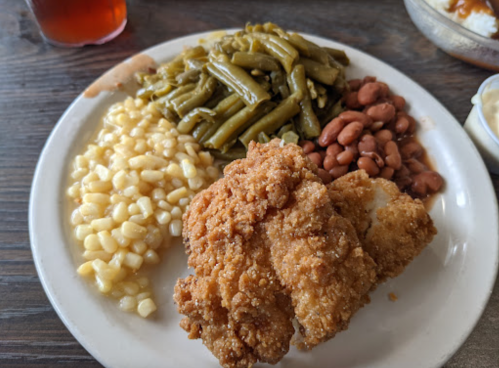 A plate of fried chicken with green beans, corn, pinto beans, and a side of coleslaw.