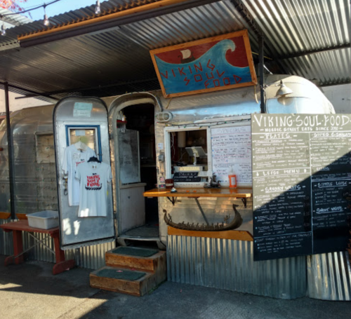 A food truck named "Viking Soul Food" with a menu board, outdoor seating, and a rustic metal exterior.