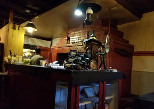 Cozy restaurant interior featuring a brick fireplace, wine rack, and warm lighting.