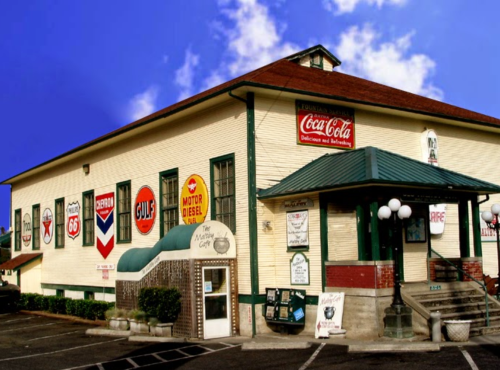 Historic building with vintage gas station signs, a green roof, and a welcoming entrance. Blue sky in the background.