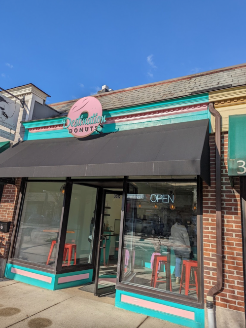 A colorful donut shop with a sign reading "Destination Donuts" and an open sign in the window.