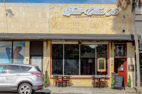 Exterior of "Better Than Sex," a dessert restaurant, featuring large windows and outdoor seating. A car is parked nearby.