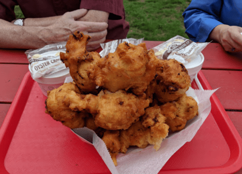 A red tray holds a large pile of golden-brown fried food, with two cups of sauce in the background.