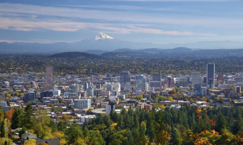 A panoramic view of Portland, Oregon, with Mount Hood in the background and autumn foliage in the foreground.