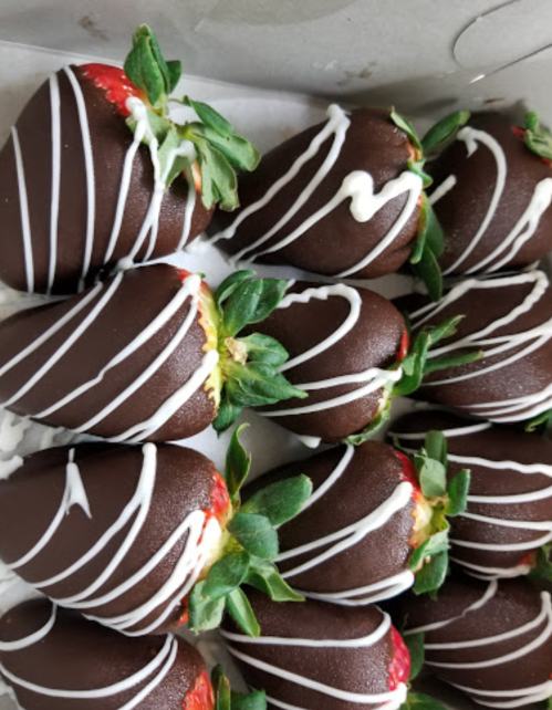A close-up of chocolate-covered strawberries drizzled with white chocolate, arranged neatly in a box.