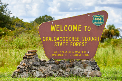 Welcome sign for Okaloacoochee Slough State Forest, highlighting clean air, water, wildlife, and recreation.